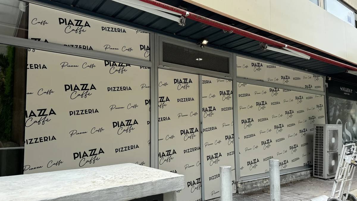 Bâche imprimée posée en façade d'une pizzeria en bord de mer sur la Côte d'Azur, avec oeillets visibles sur tout le pourtour.