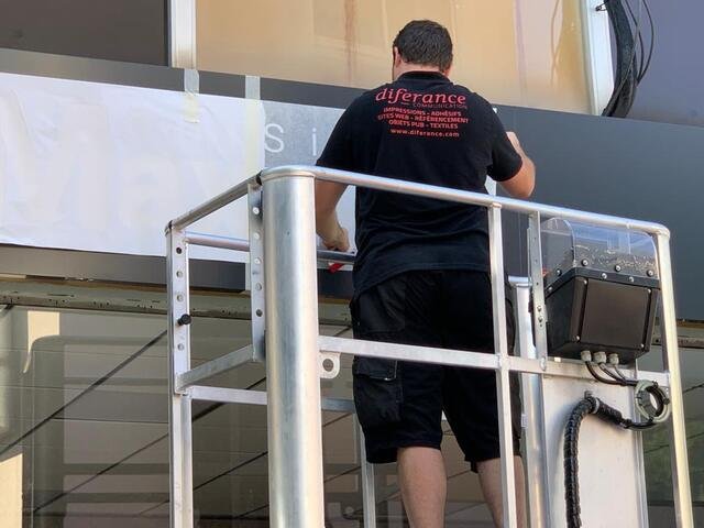Technicien Diferance appliquant un habillage adhésif sur un bâtiment professionnel